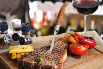 T-Bone steak barbecue with fried potato and red wine on wood table