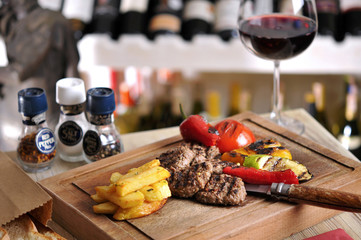 Meatball barbecue with fried potato and red wine on wood table