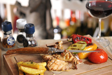 Chicken barbecue with fried potato and red wine on wood table
