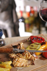 Chicken barbecue with fried potato and red wine on wood table
