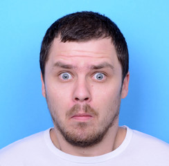 Fototapeta premium Portrait of man with dusgusted gesture against blue background