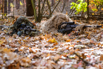 Team of snipers aiming at target in forest/Two sniper in camouflage suits with rifles in hands hide in the woods