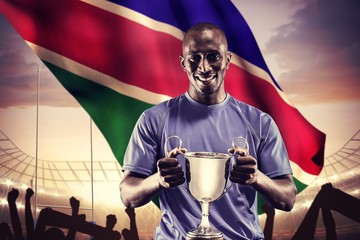 Composite image of portrait of happy athlete holding trophy