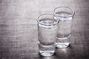 Vodka glasses on retro linen fabric texture. 
