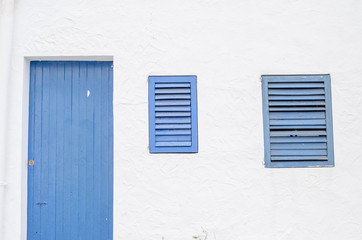 Blue window and door made out of wood and white wall.