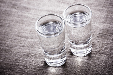 Vodka glasses on retro linen fabric texture. 