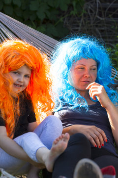 Little girls in brightly colored carnival wigs in the setting su