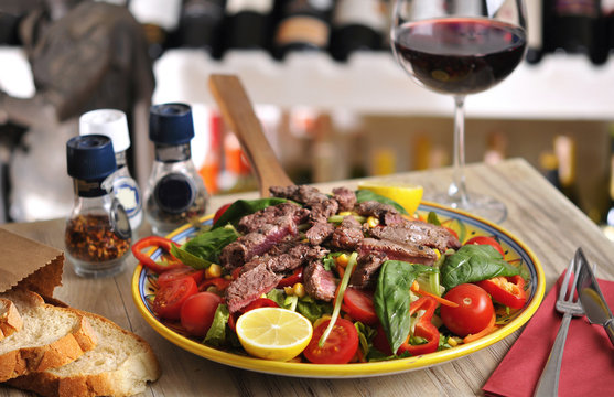 Seasonal salad with beef and red wine on wooden table