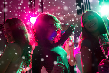 smiling friends with glasses of champagne in club