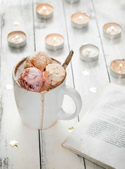 Hot chocolate with marshmallows and candle lights and a book
