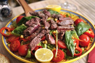 Seasonal salad with beef and red wine on wooden table