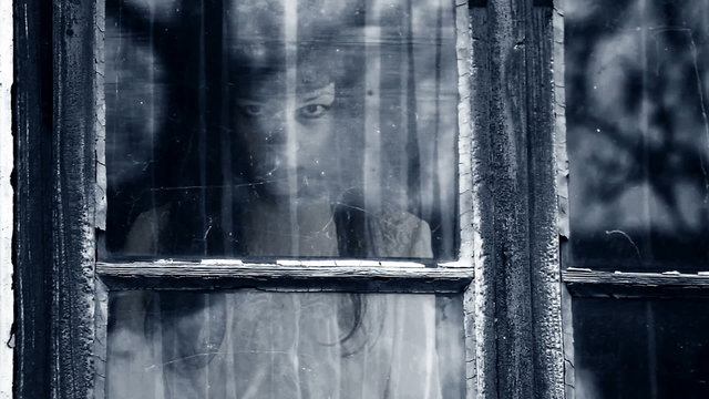 Horror scene of female ghost behind grunge window.