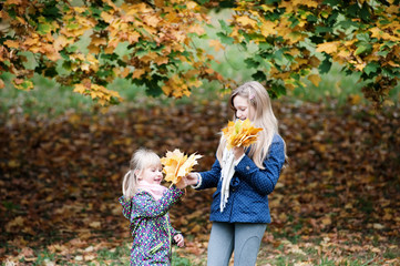 Two girls playing with autumn leaves