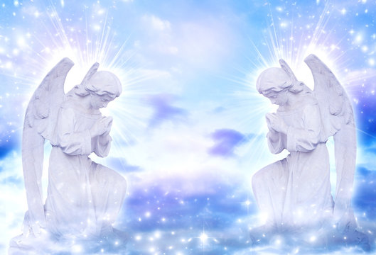 two praying angels with rays of light over blue sky with stars