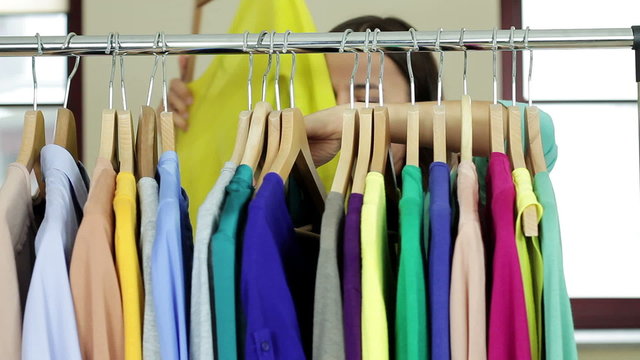 Female customer choosing clothes from rack in clothing store