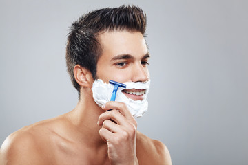 Young man shaving beard