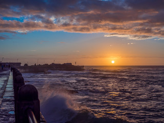Dramatic sunset in Cape Town with waves crashing on the promenad