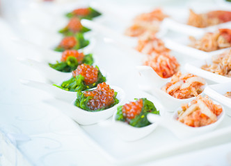red caviar close-up in white spoons on banquet