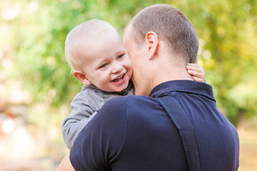 Happy father and his son outdoors. Child hugging daddy.