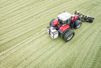 Roter Traktor mit Planierschild auf einem Silomaishaufen, Luftbild