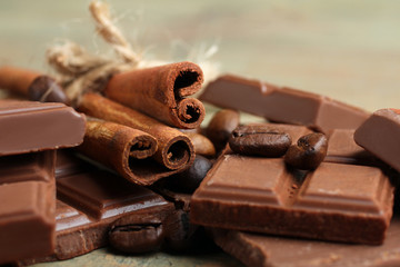 tender milk chocolate and cinnamon with coffee beans on wooden background