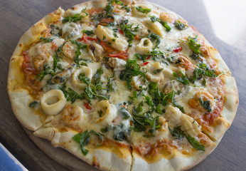 Sea basil pizza on a wooden tray. Peper