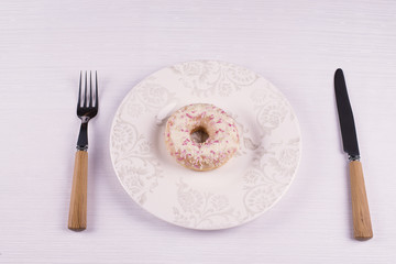 Donut on a plate with a knife and fork
