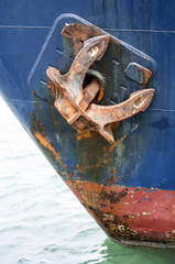 Rusty anchor of old blue ship closeup
