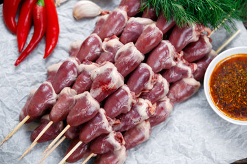 Ready to cook Duck Heart stringed on skewers BBQ , chili pepper. decorated with greens and vegetables. background.