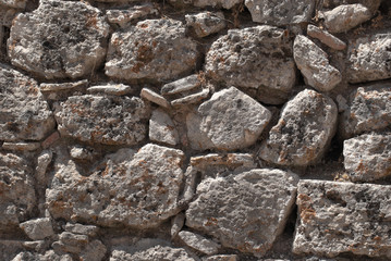 Fragment of the fortress wall of light-colored stone, covered with moss, in the ancient city of Corinth. The Peloponnese, Greece.