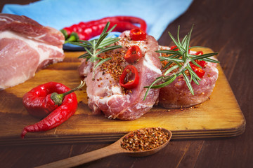 Fresh sliced raw meat on a wooden cutting board with spices and onions