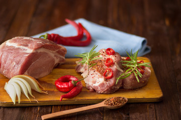 Fresh sliced raw meat on a wooden cutting board with spices and onions