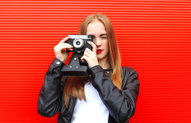 Fashion pretty woman with old retro camera over red background