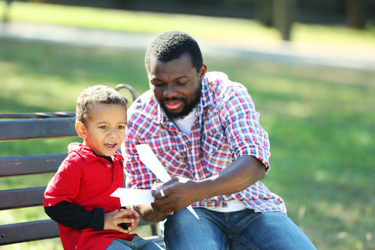 Father And Son Making Paper Plane In The Park