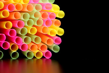 viel bunte trinkhalme vor schwarzem Hintergrund