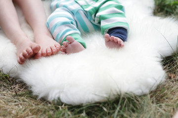 two pair of children's feet lays on white sheep fur