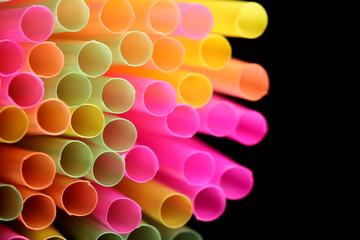 viel bunte trinkhalme vor schwarzem Hintergrund