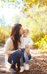 Happy loving mother kissing child in autumn warm day