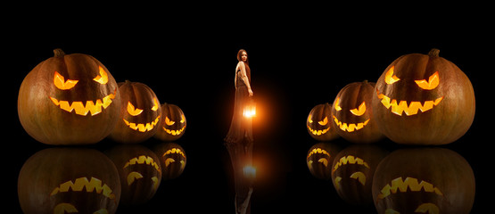 Beautiful witch with the magic lantern. Halloween pumpkins on th