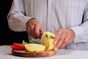 Close up on male hands cutting pepper, making salad. Chief cutting vegetables. Healthy lifestyle, diet food