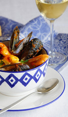 french soup Bouillabaisse with mussels, clams, langoustines, squid, cod, trout in white bowl with...