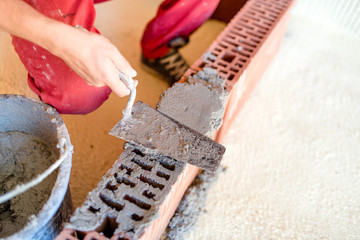 industrial worker with spatula and putty knife using mortar for creating brick walls