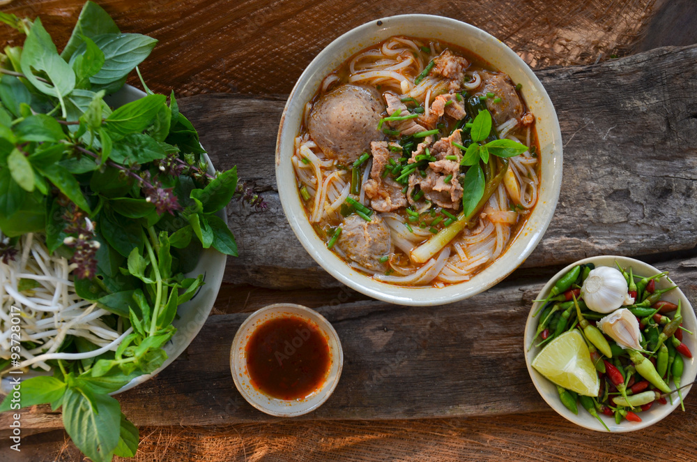 Wall mural Pho Vietnamese beef soup on a wooden background