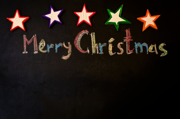Merry Christmas written with chalk on a black background with wo