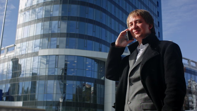 Happy businessman using cell phone outside office