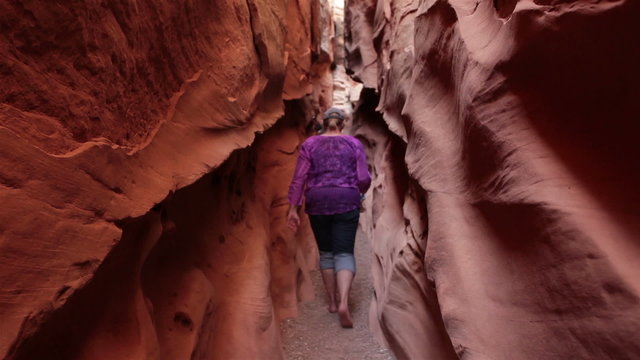 Woman hikes narrow desert slot canyon HD 1578