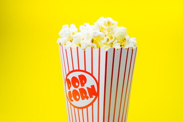 Classic box cinema popcorn on yellow background..