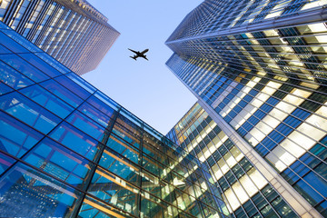 A jet airplane silhouette with business office towers background © alice_photo