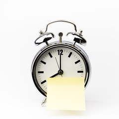 Alarm clock with sticky paper note on white background