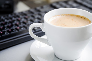 Coffee cappuccino, keyboard and mouse on the table